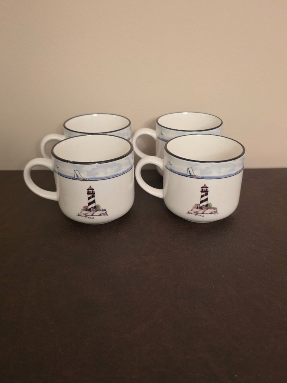 Set of 4 - Round ceramic coffee cups featuring a coastal lighthouse pattern.